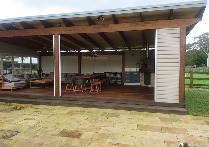 a patio with comfy chairs and dining tables with outdoor shutters