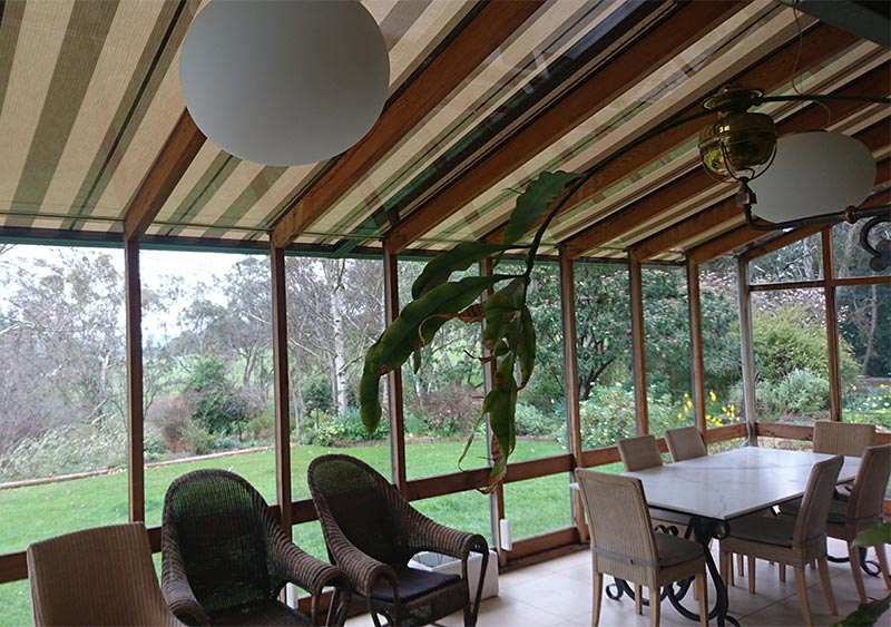 A patio built-in wooden style covered with awning with comfy chairs and table