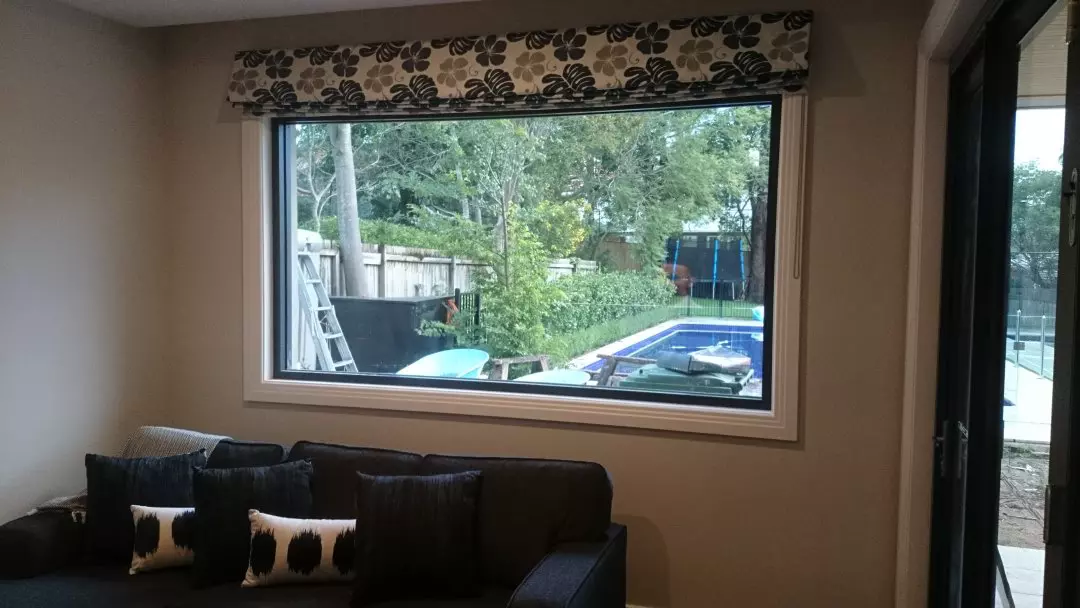 Roman blinds that have been folded and featuring a cozy couch.